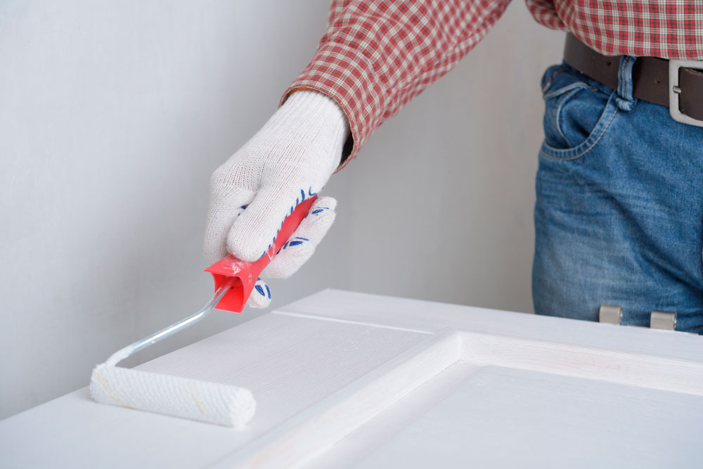Pintor muestra cómo pintar una puerta de madera en color blanco
