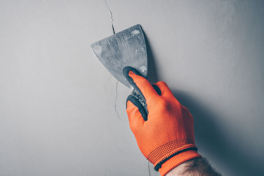 Persona prepara una pared para pintarla